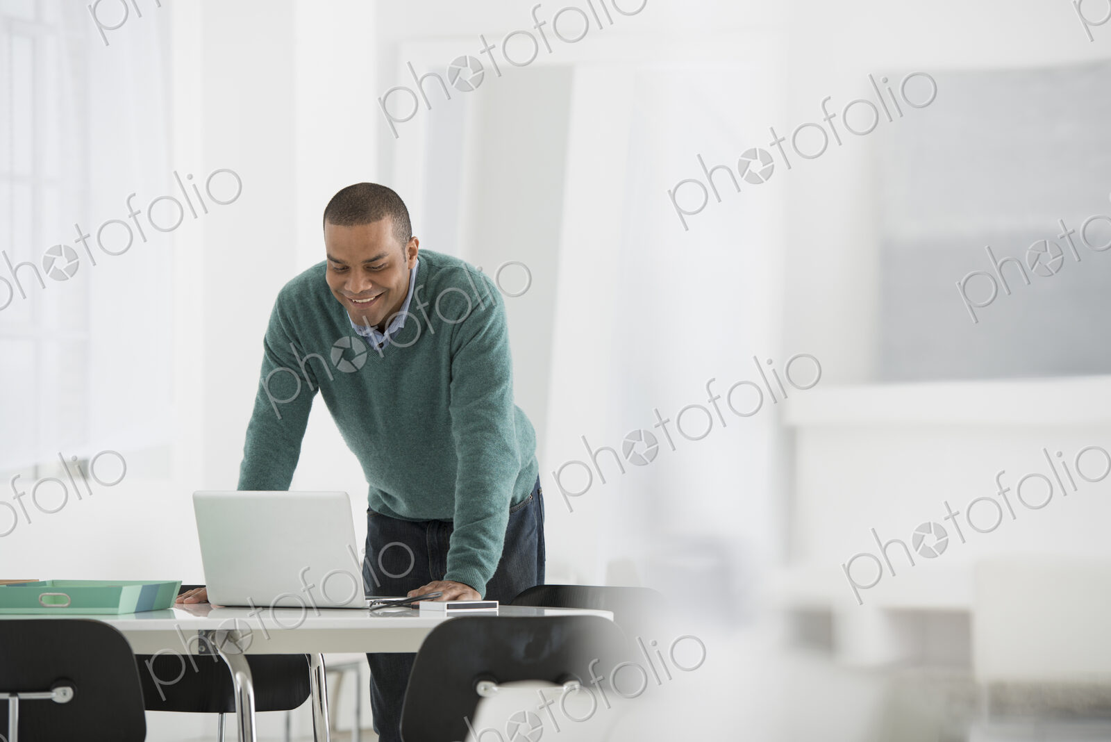 An office in the city. Business. A man standing over a desk, leaning down to use a…