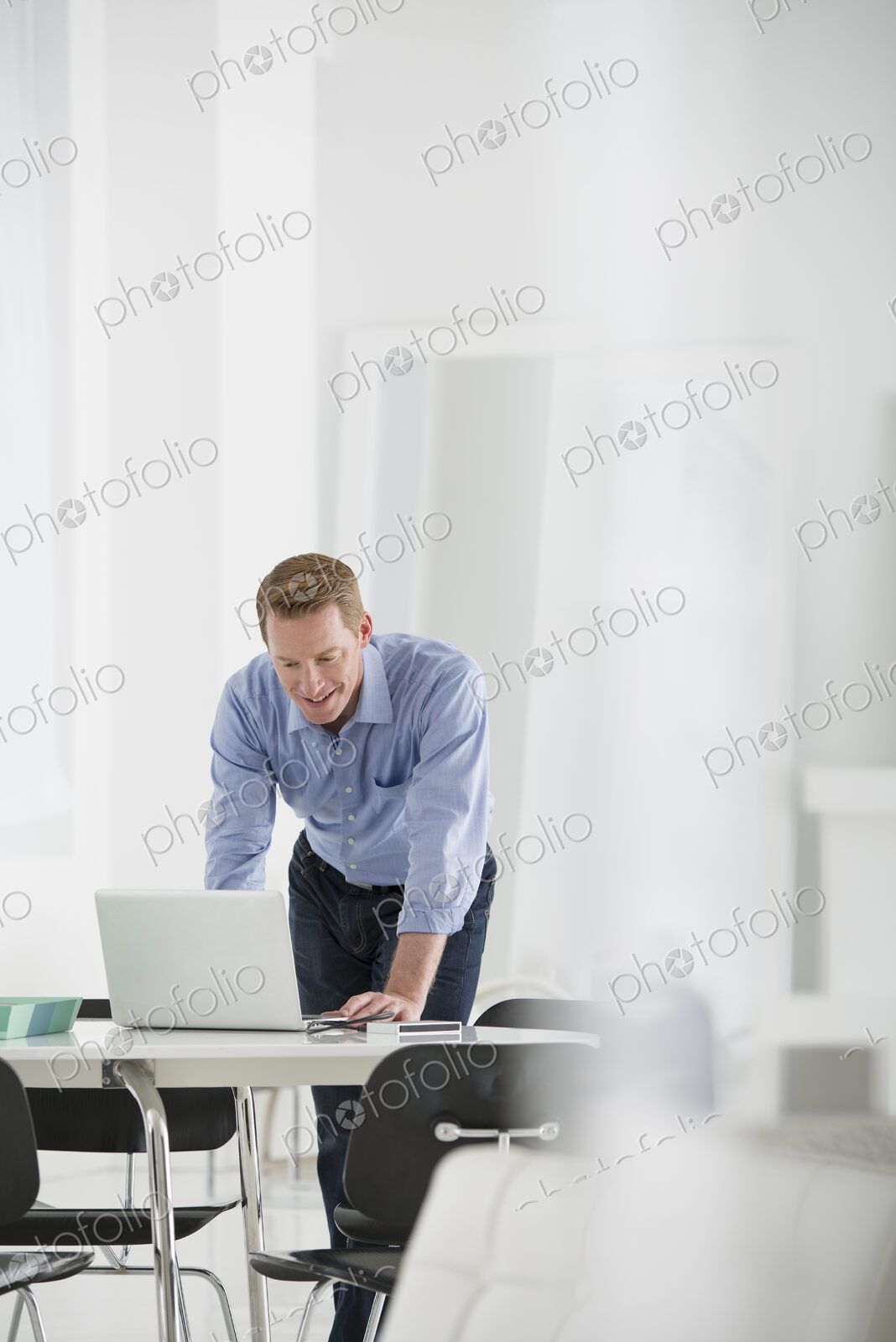 An office in the city. Business. A man standing over a desk, leaning down to use a…