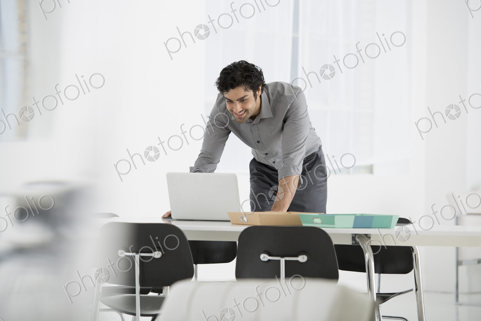 An office in the city. Business. A man standing over a desk, leaning down to use a…