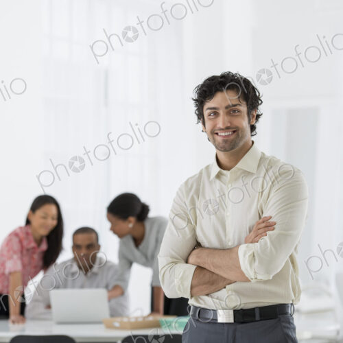 An office in the city. Business. A man standing with his arms folded, and three people…