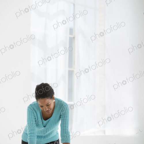 An office in the city. Business. A woman leaning over a desk using a laptop computer.