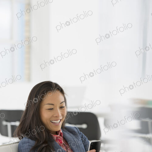 An office in the city. Business. A woman seated in a comfortable chair, checking her… An office in the city. Business. A woman seated in a comfortable chair, checking her…