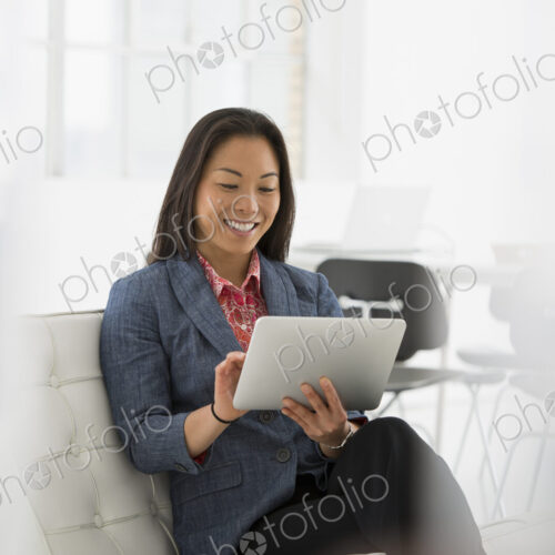 An office in the city. Business. A woman sitting down using a digital tablet. An office in the city. Business. A woman sitting down using a digital tablet.