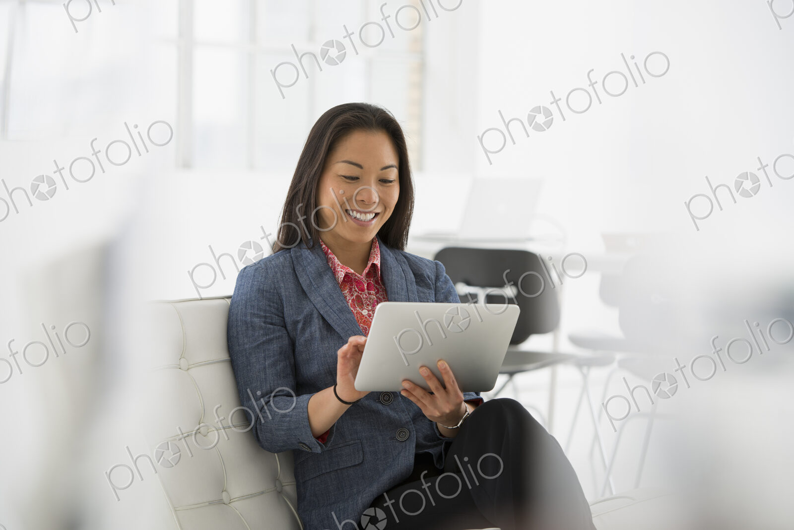 An office in the city. Business. A woman sitting down using a digital tablet.