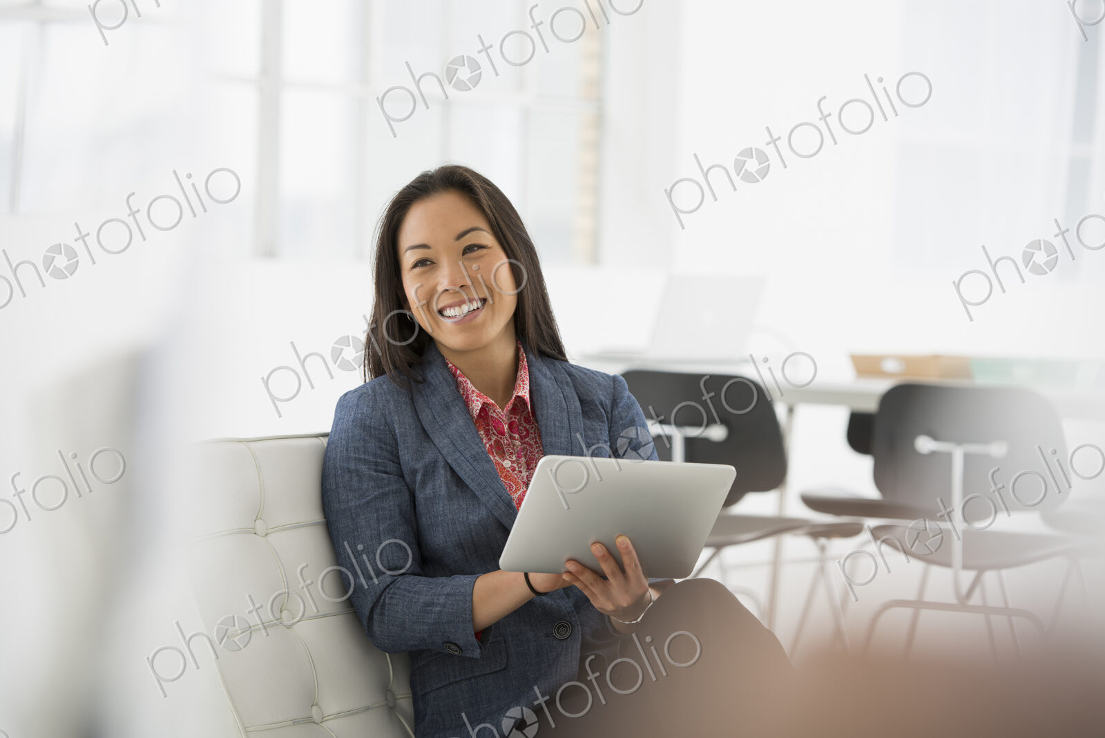An office in the city. Business. A woman sitting down using a digital tablet.