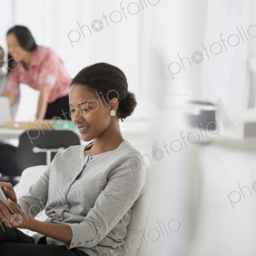 An office in the city. Business. A woman sitting down using a digital tablet. Two…