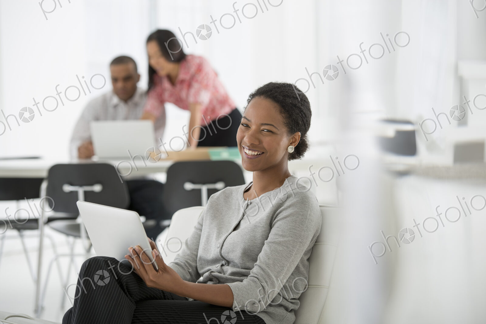 An office in the city. Business. A woman sitting down using a digital tablet. Two…