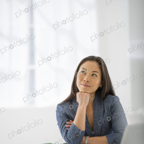 An office in the city. Business. A woman sitting relaxing, with her chin on her hand.…