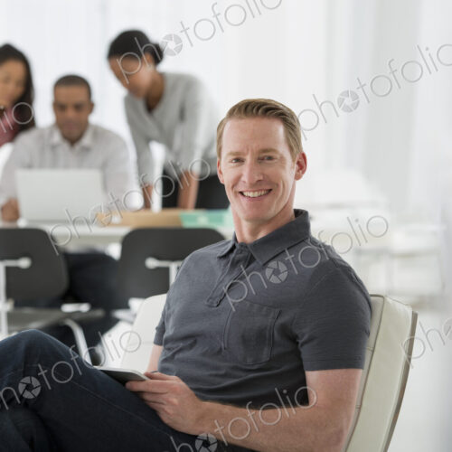 An office in the city. Business. Four people, one man sitting on a soft chair, and…