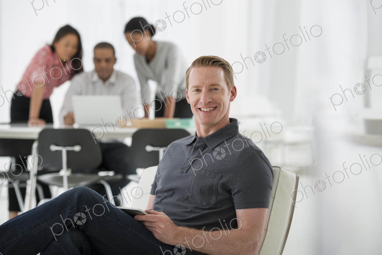 An office in the city. Business. Four people, one man sitting on a soft chair, and…