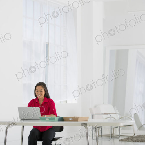 An office in the city. Light and airy working environment. A woman seated using a laptop. An office in the city. Light and airy working environment. A woman seated using a laptop.
