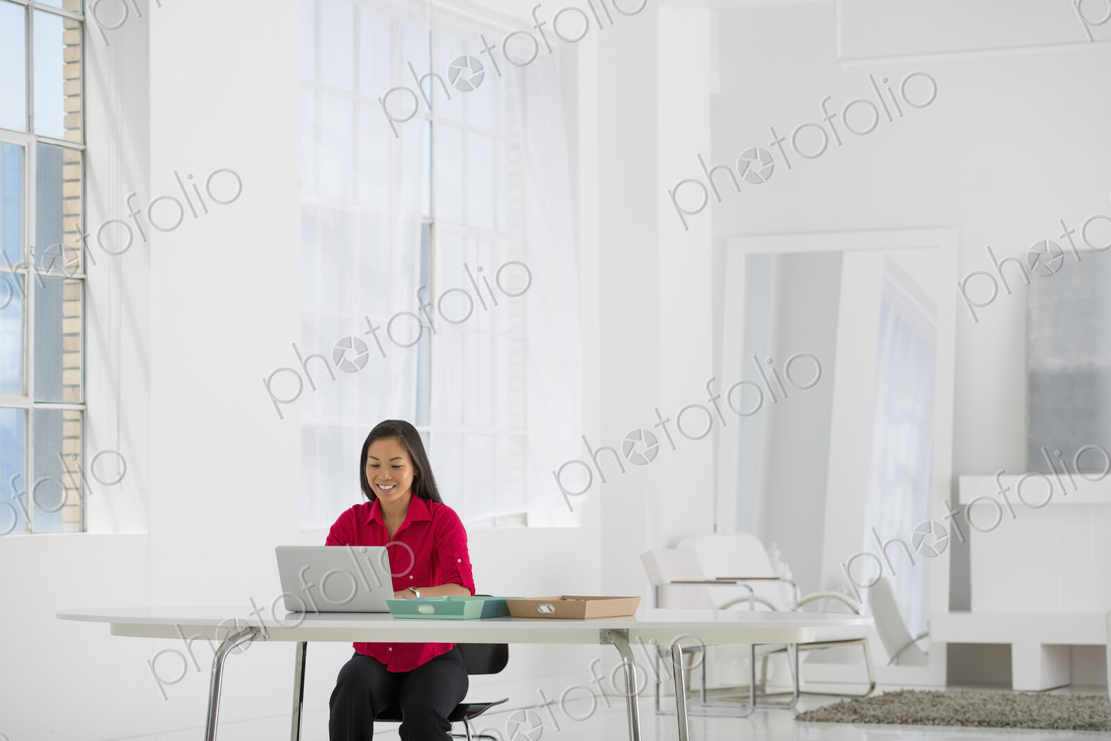 An office in the city. Light and airy working environment. A woman seated using a laptop.