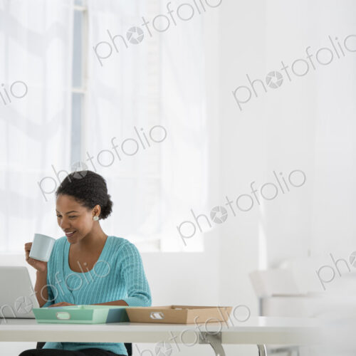 An office in the city. Light and airy working environment. A woman seated using a laptop.