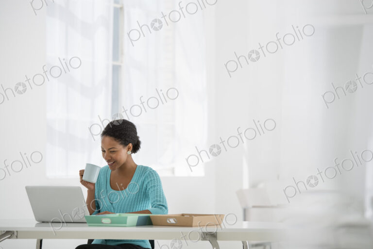 An office in the city. Light and airy working environment. A woman seated using a laptop.