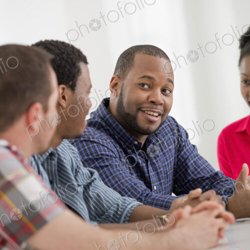 An office interior flooded with light. A group of four people, two men and two women…