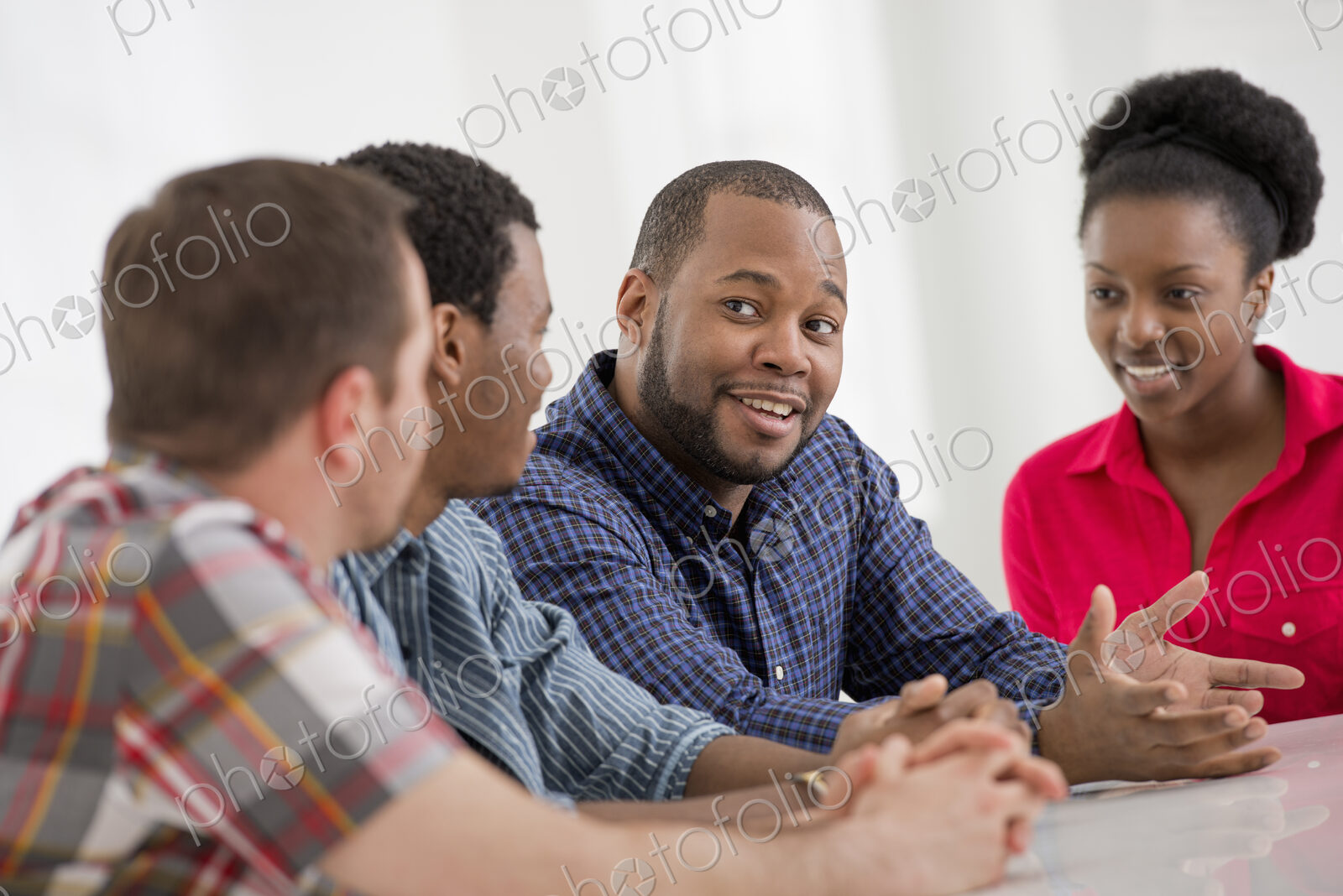 An office interior flooded with light. A group of four people, two men and two women…