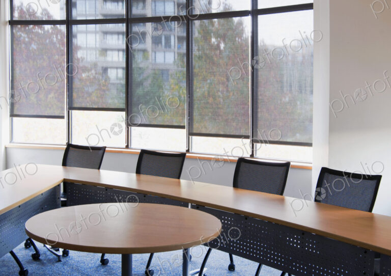An office meeting room with windows, a long table and chairs.