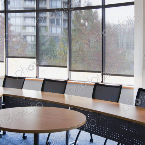 An office meeting room. Narrow table set at an angle with a small round table at the…