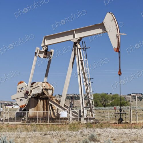 An oil pump jack operates in Rozet, Wyoming, set against a clear blue sky. The…