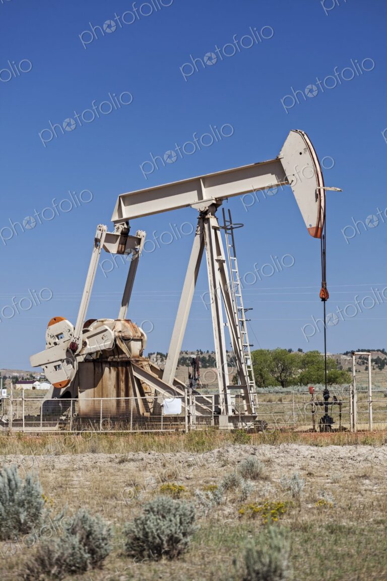 An oil pump jack operates in Rozet, Wyoming, set against a clear blue sky. The…
