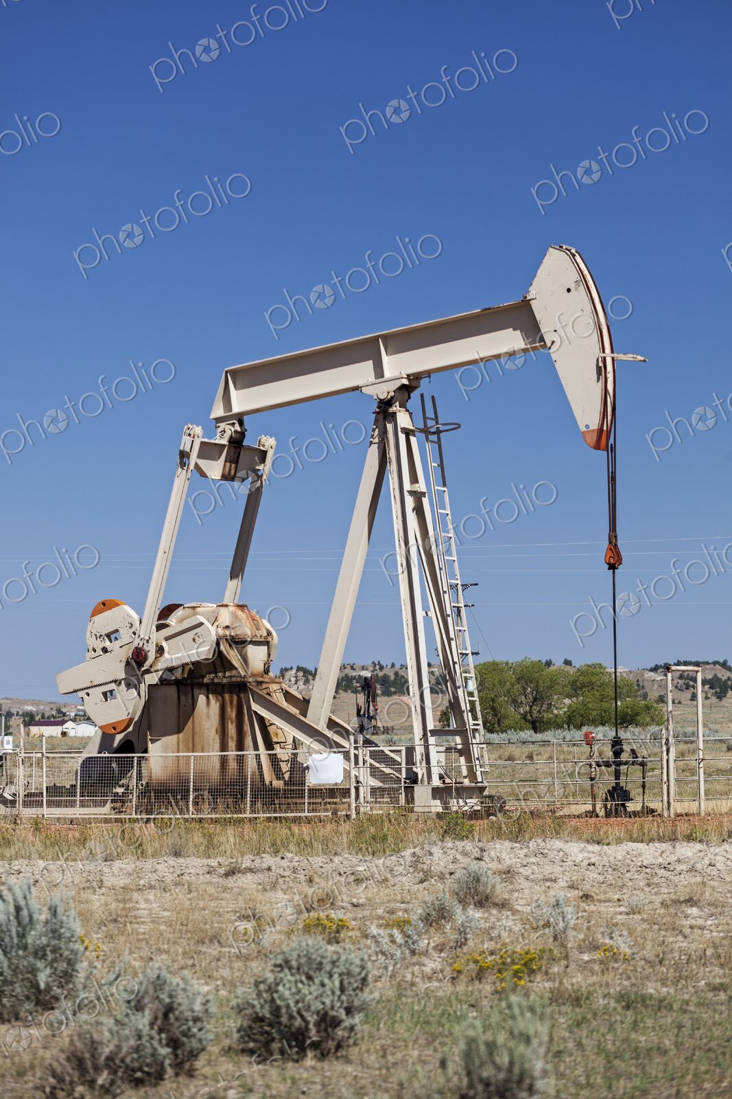 An oil pump jack operates in Rozet, Wyoming, set against a clear blue sky. The…