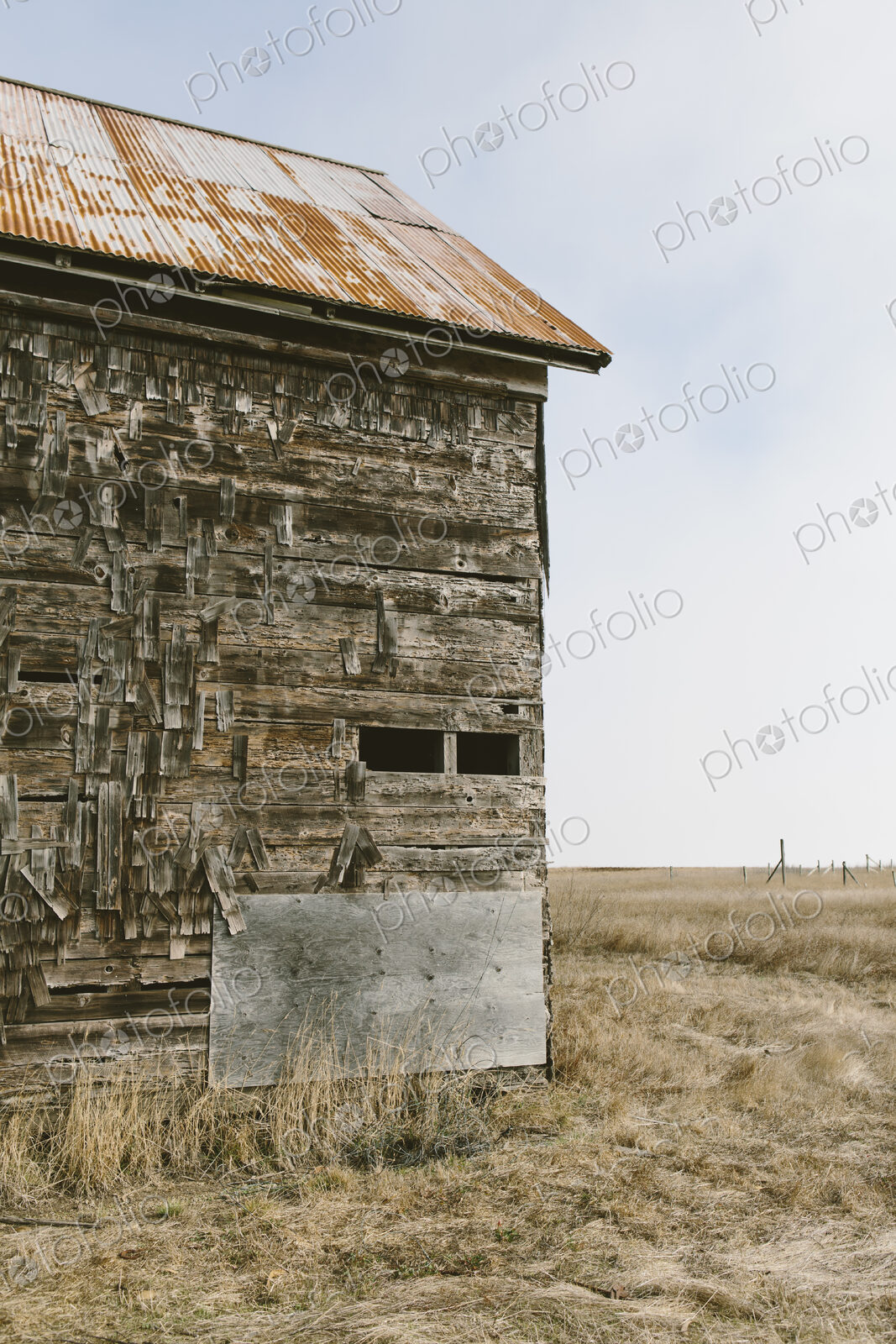 An old abandoned farmhouse with wooden shingle tiles on the walls. Silvery grey colours.