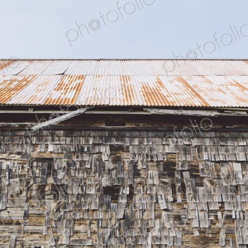 An old farmhouse with wooden shingle tiles on the walls and corrugated iron roof An old farmhouse with wooden shingle tiles on the walls and corrugated iron roof
