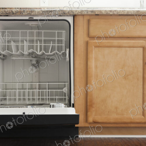 An open dishwasher in a kitchen with wooden fitted units. An open dishwasher in a kitchen with wooden fitted units.