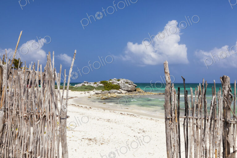 An opening in the fence onto a white sand beach