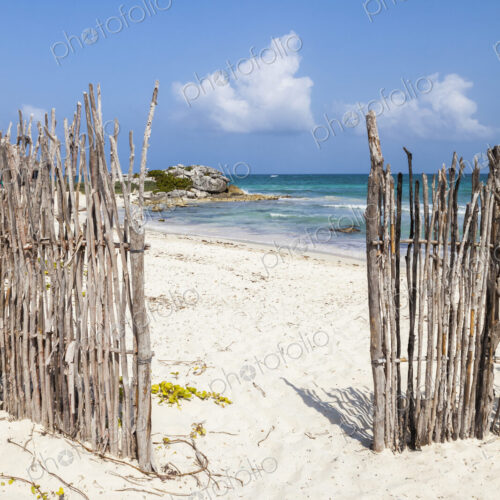 An opening in the fence onto a white sand beach An opening in the fence onto a white sand beach