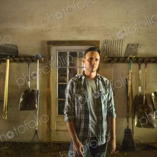 An organic farm in the Catskills. A man standing in a barn with equipment stored…