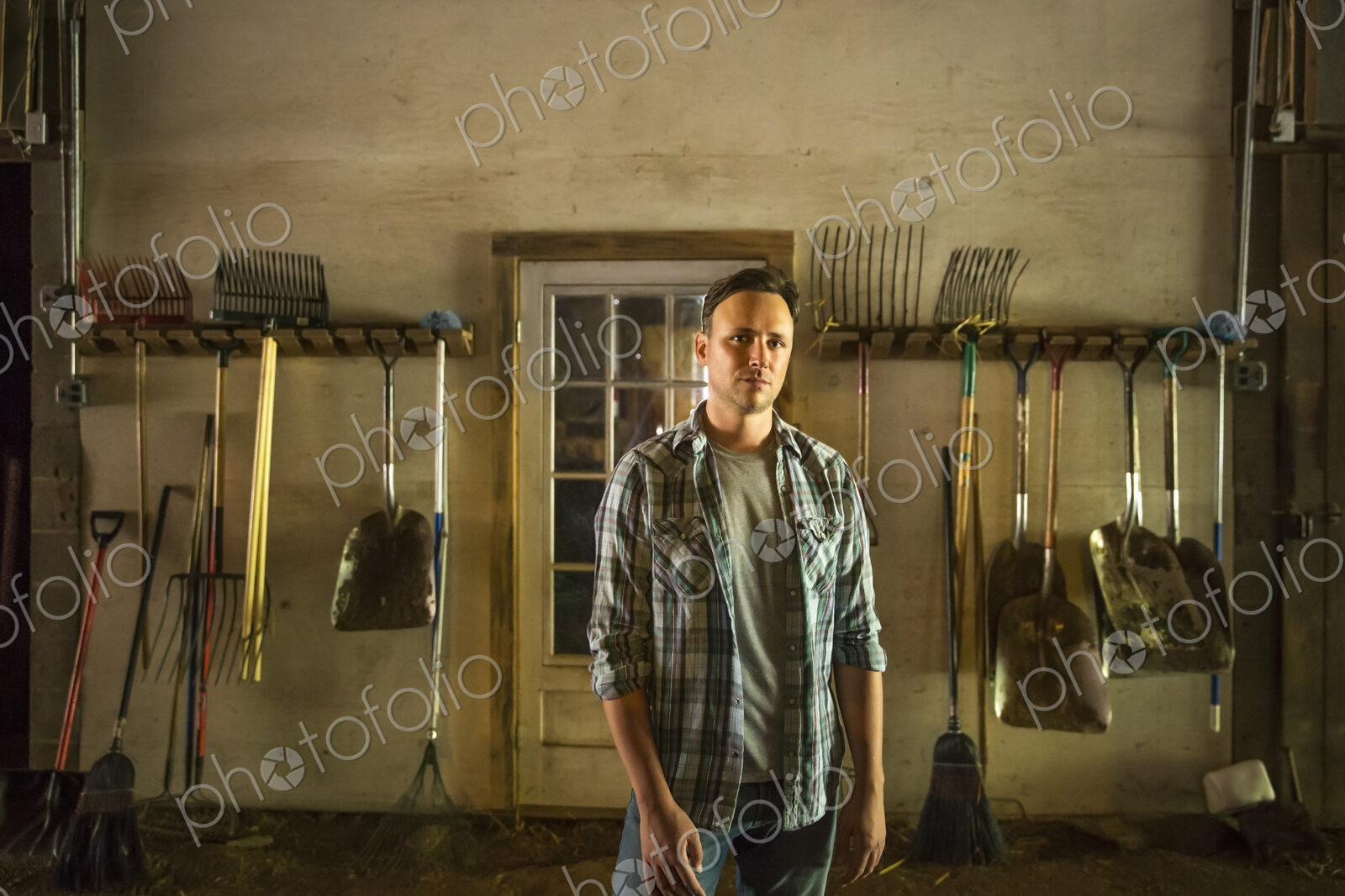 An organic farm in the Catskills. A man standing in a barn with equipment stored…
