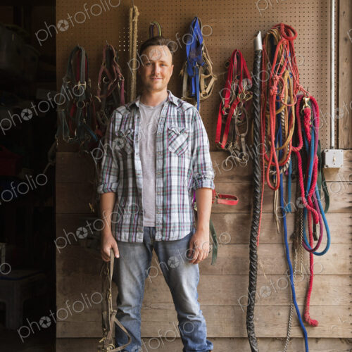 An organic farm in the Catskills. A man standing in a tack room in a stable.