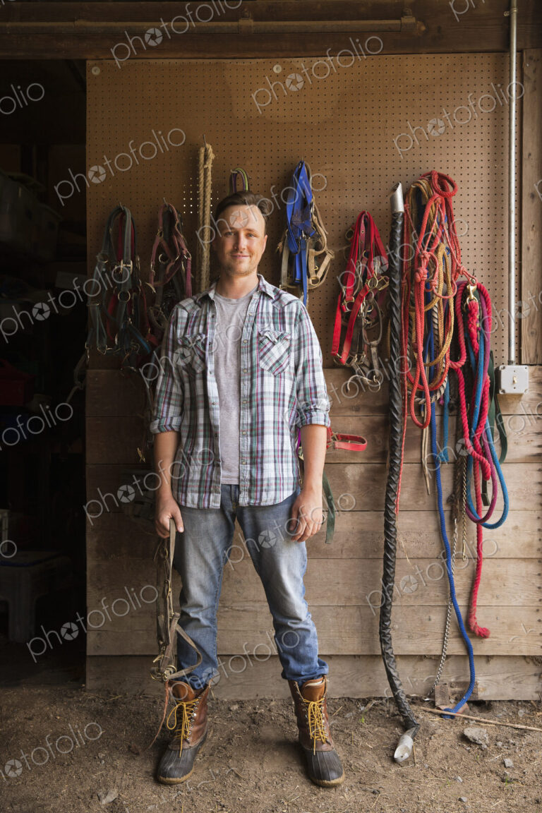 An organic farm in the Catskills. A man standing in a tack room in a stable.