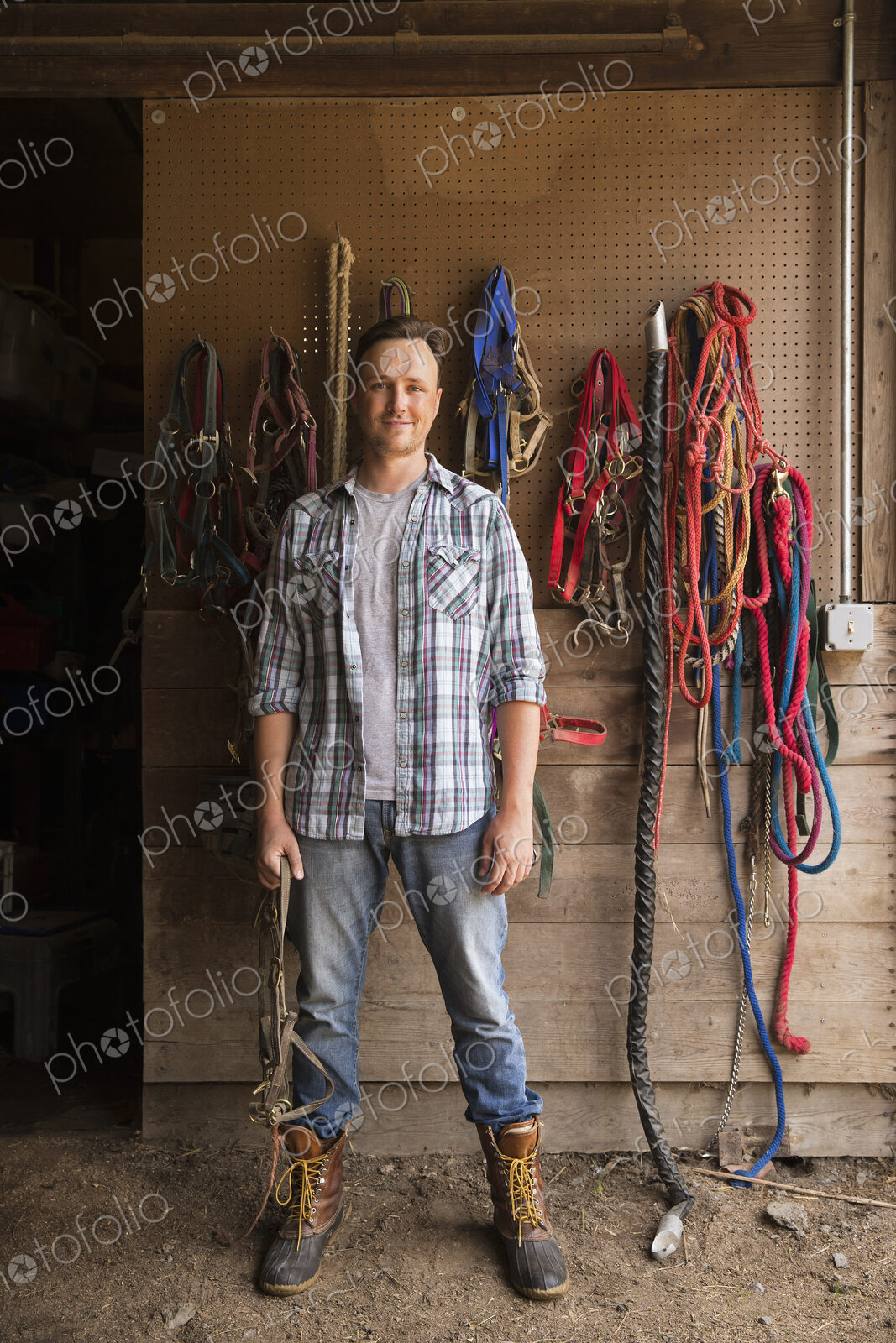 An organic farm in the Catskills. A man standing in a tack room in a stable.