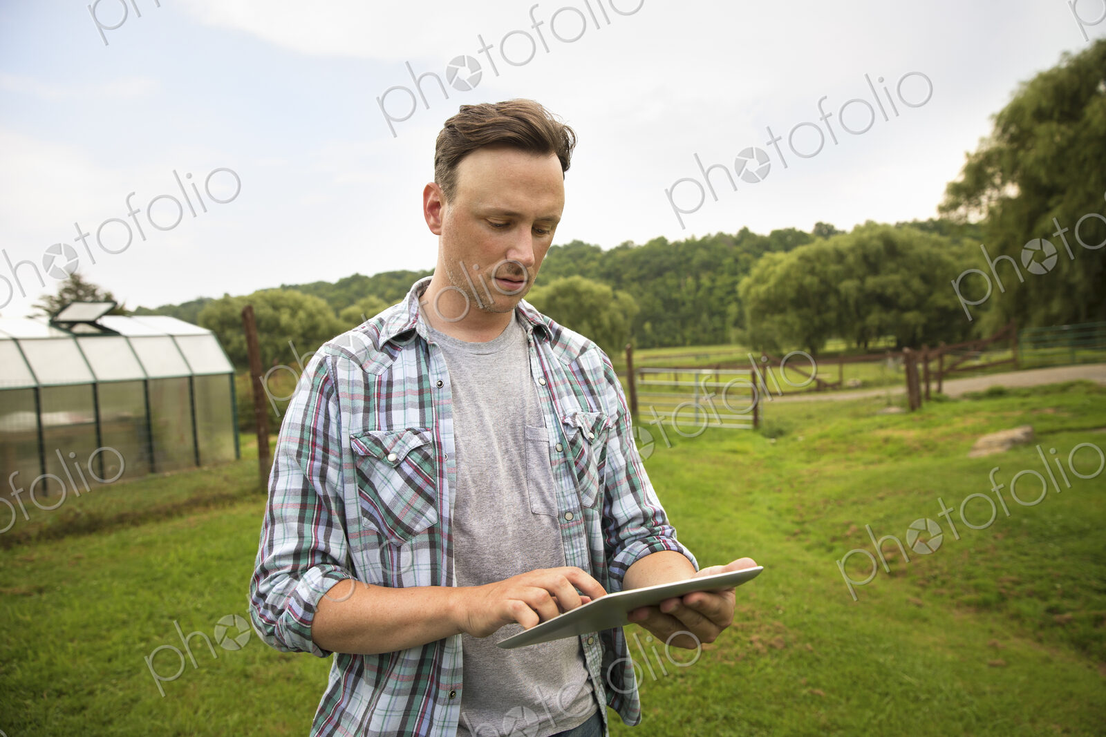 An organic farm in the Catskills. A man using a digital tablet in a grass paddock.