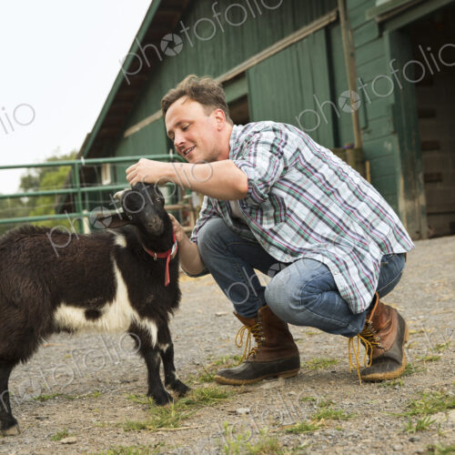 An organic farm in the Catskills. A man with a small black goat.