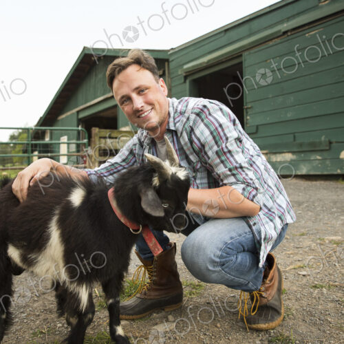 An organic farm in the Catskills. A man with a small goat on a halter. An organic farm in the Catskills. A man with a small goat on a halter.