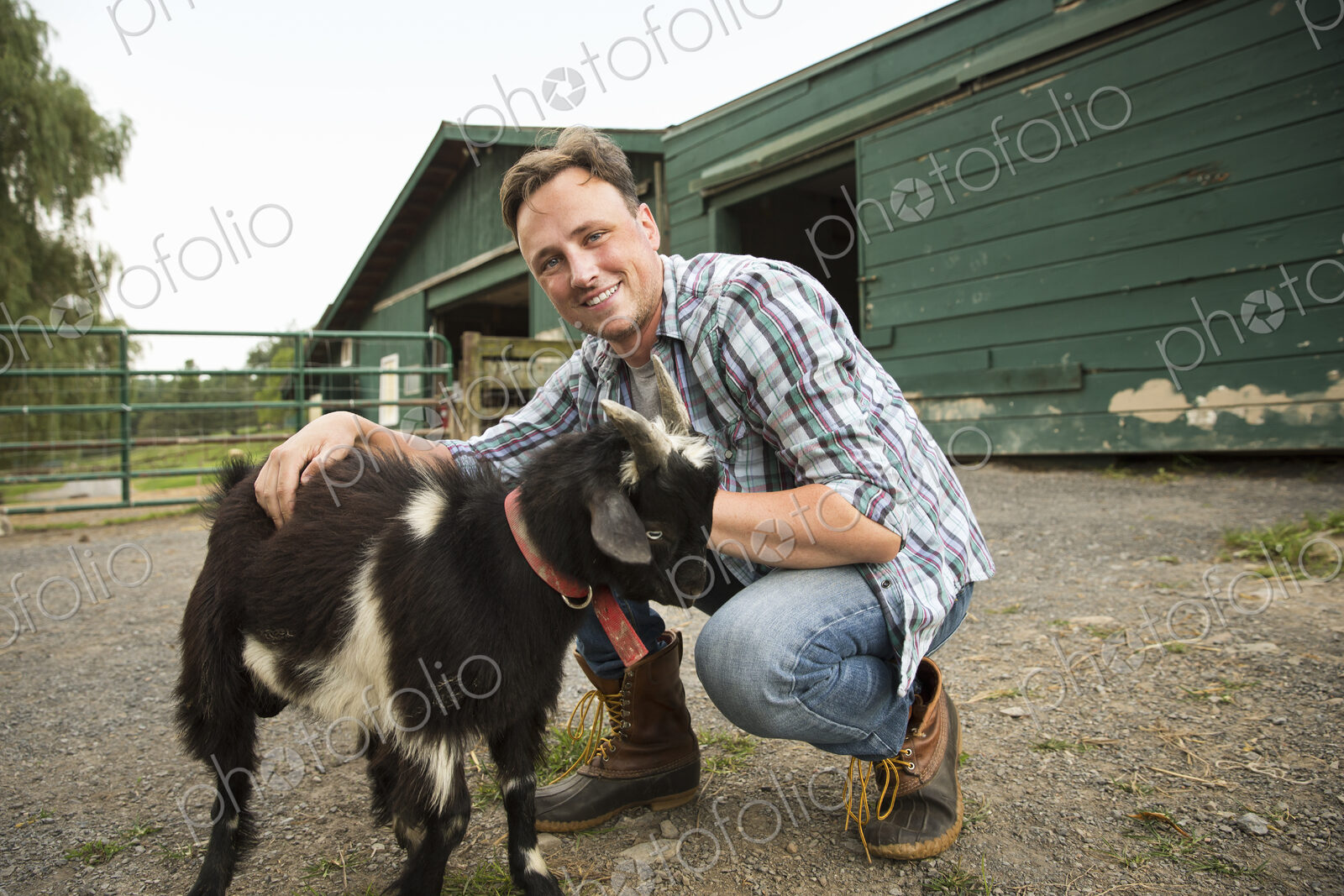An organic farm in the Catskills. A man with a small goat on a halter.
