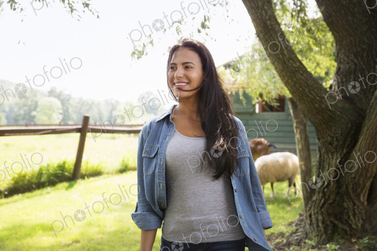 An organic farm in the Catskills. A woman in a paddock with a sheep.