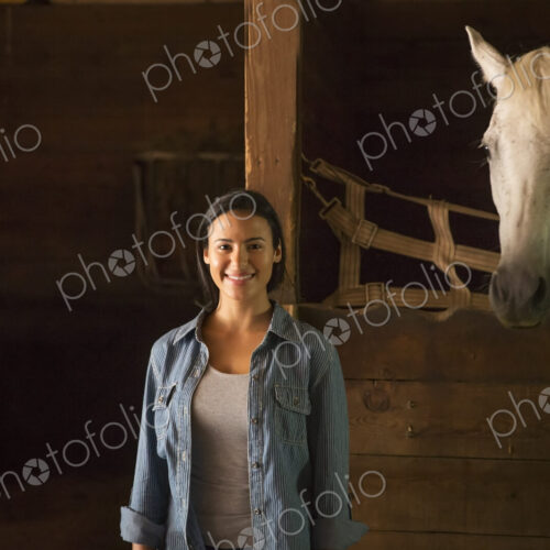 An organic farm in the Catskills. A woman standing in a stable, with a white horse…
