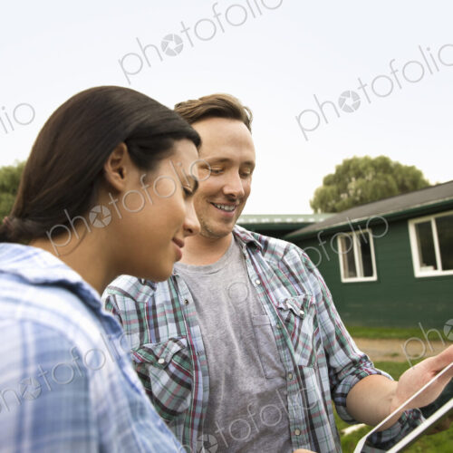 An organic farm in the Catskills. Two people using a digital tablet outdoors.