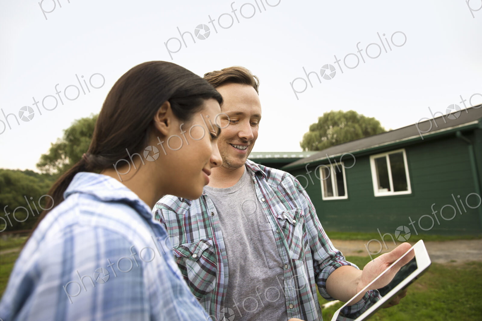 An organic farm in the Catskills. Two people using a digital tablet outdoors.