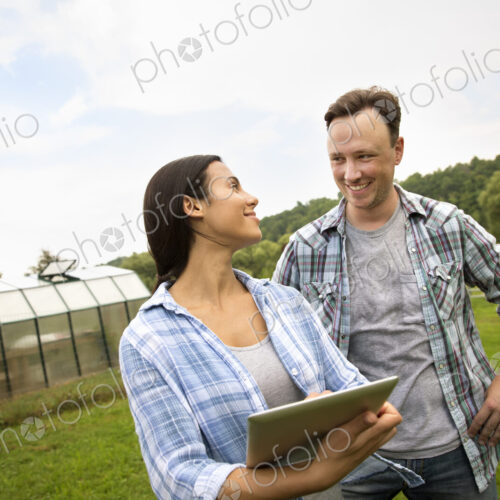 An organic farm in the Catskills. Two people using a digital tablet outdoors.