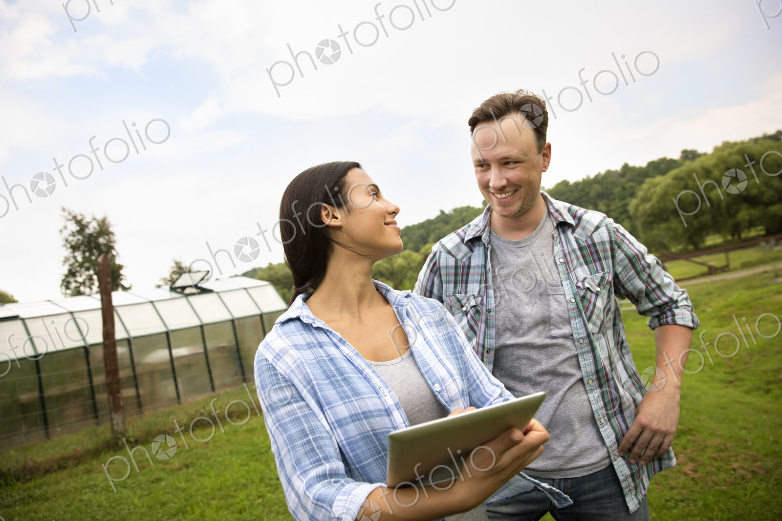 An organic farm in the Catskills. Two people using a digital tablet outdoors.