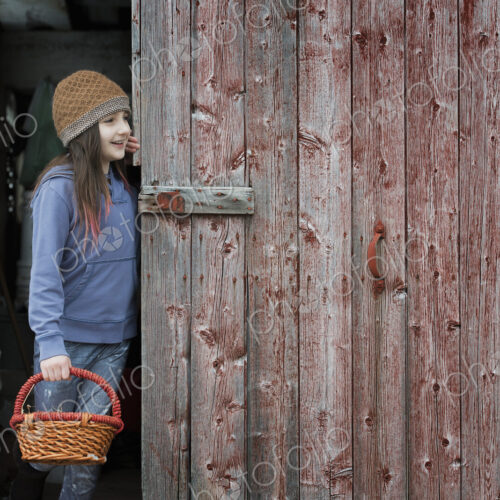 An organic farm in upstate New York, in winter. A girl in a barn doorway with a basket. An organic farm in upstate New York, in winter. A girl in a barn doorway with a basket.