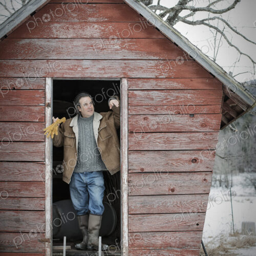 An organic farm in upstate New York, in winter. A man standing in the doorway of a…