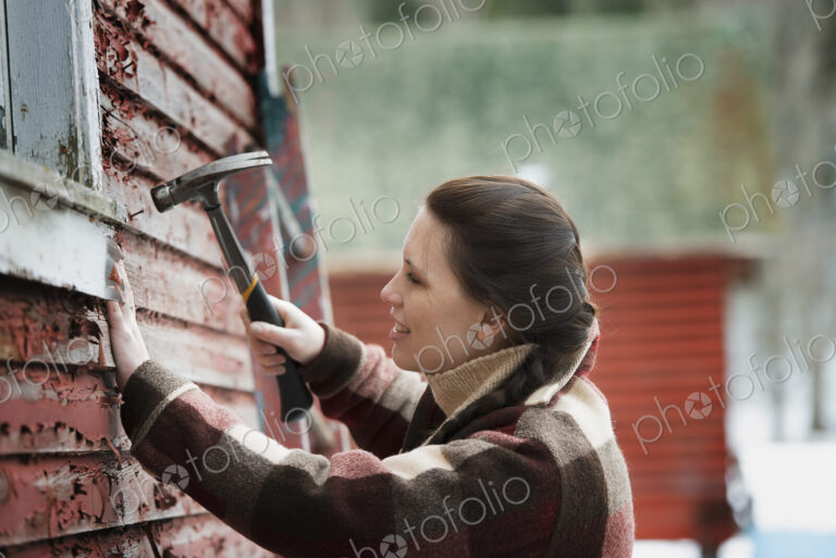 An organic farm in upstate New York, in winter. A woman with a hammer repairing the…