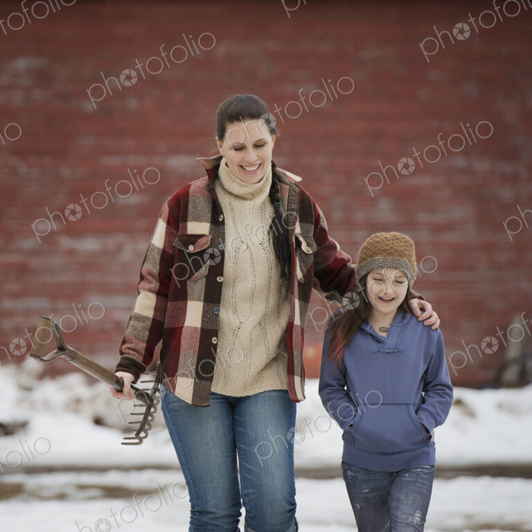 An organic farm in winter in New York State, USA. A woman and a young girl walking…