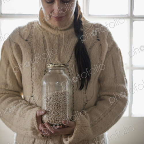 An organic farm in winter in New York State, USA. A woman in a cable knit sweater,…